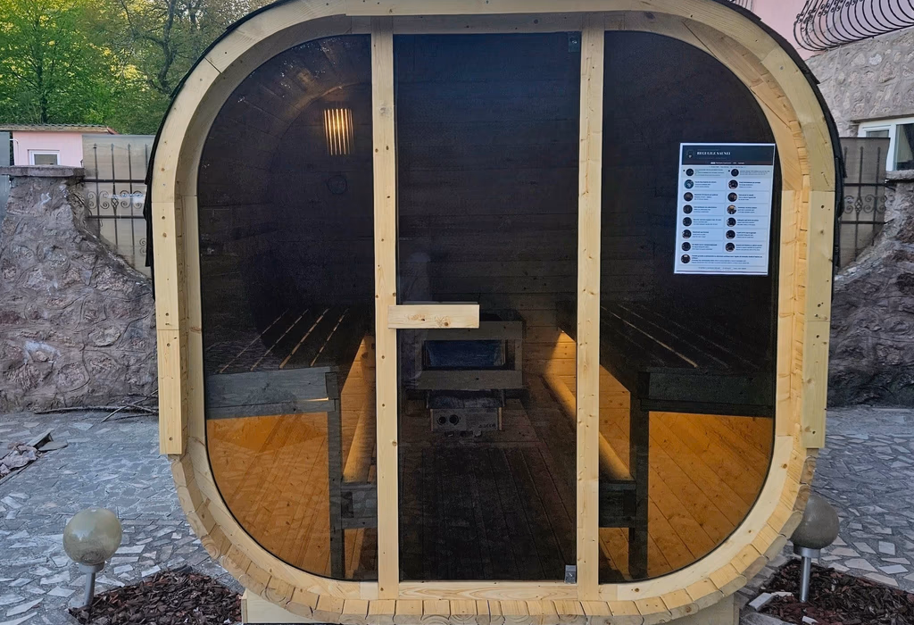 Sauna finlandeză văzută din față, interior iluminat cald cu bănci și sobă
