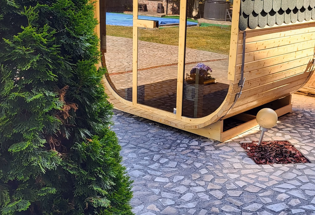 Sauna finlandeză din lemn cu acoperișul verde și pădurea Moneasa în fundal